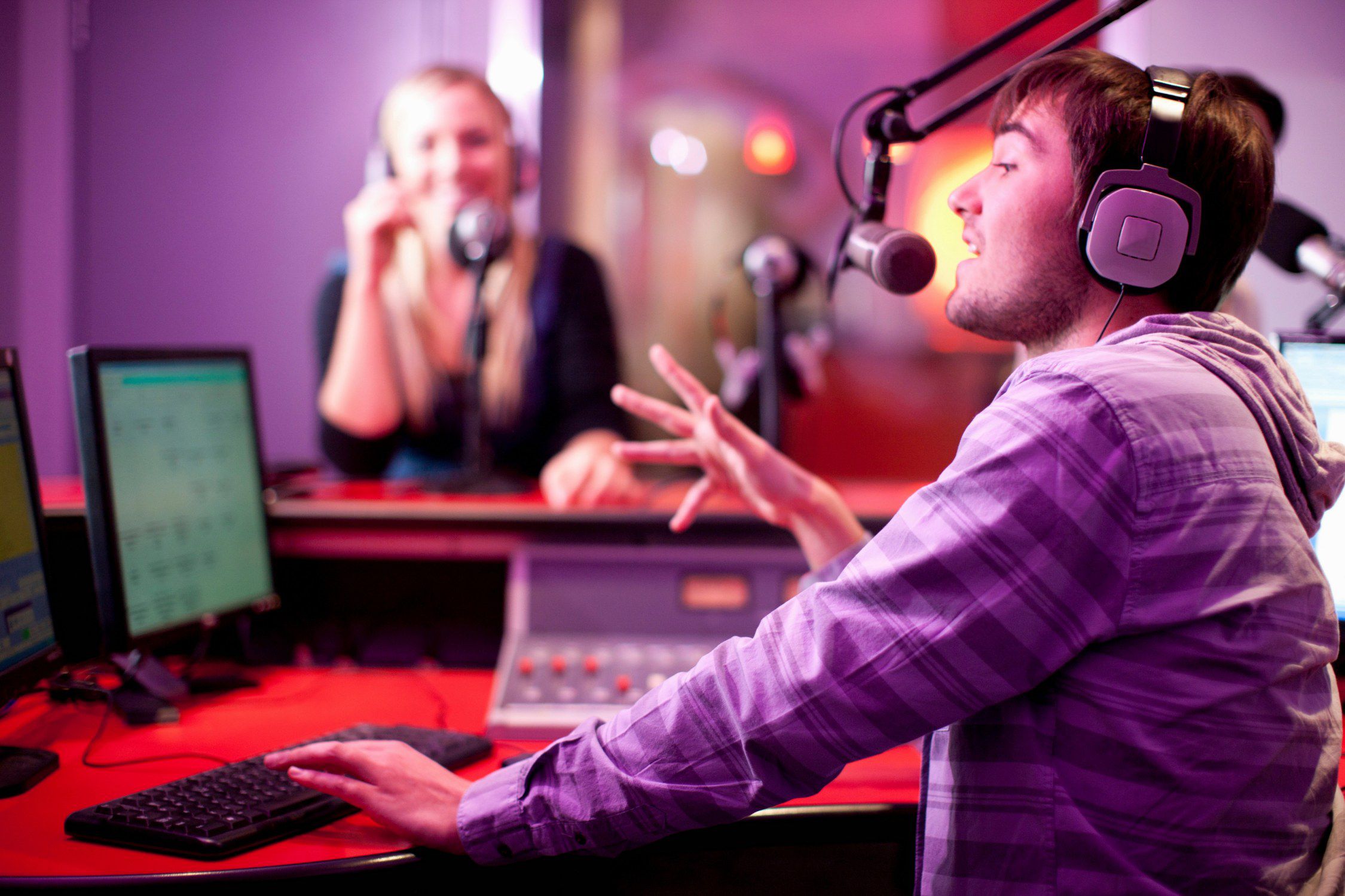 Voice over artists animatedly converse in a studio, symbolizing the dynamic impact of AI voice technologies on speech-based applications.
