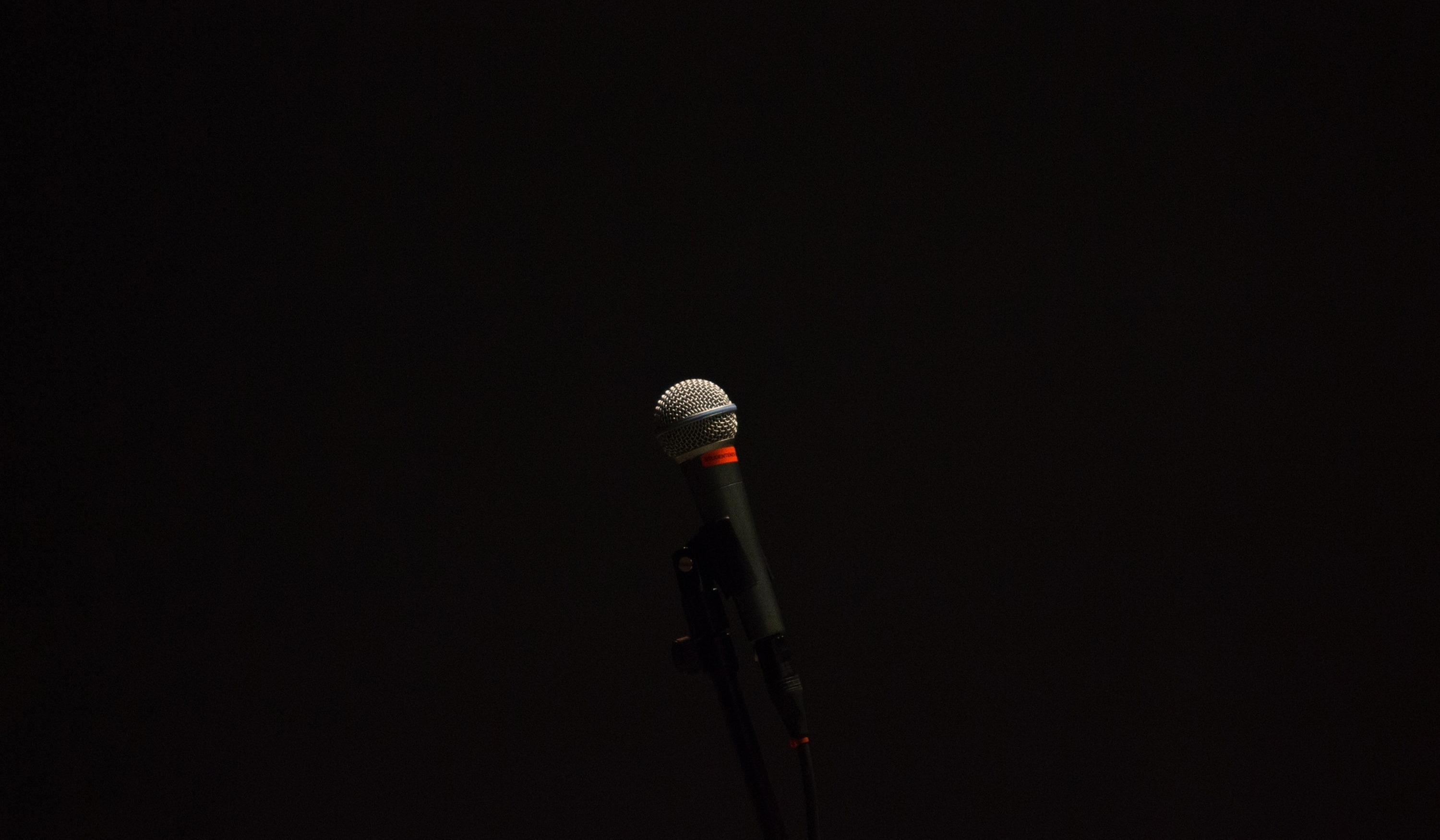 A single microphone illuminated against a dark backdrop, representing the potential of singing voice synthesis technology.